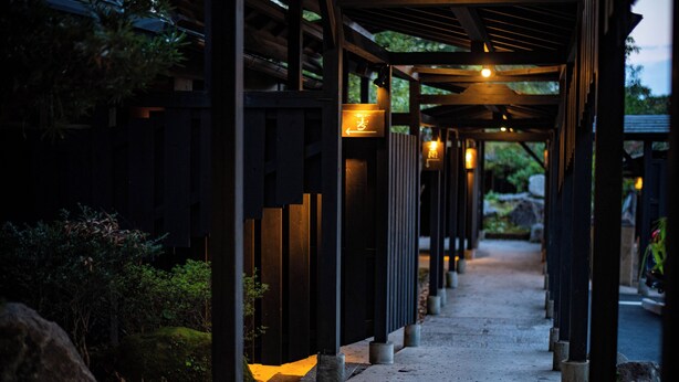 A covered walkway with directional signs and a pathway leading to a building. - Beppu Tabiyado Sainokou (Beppu)
