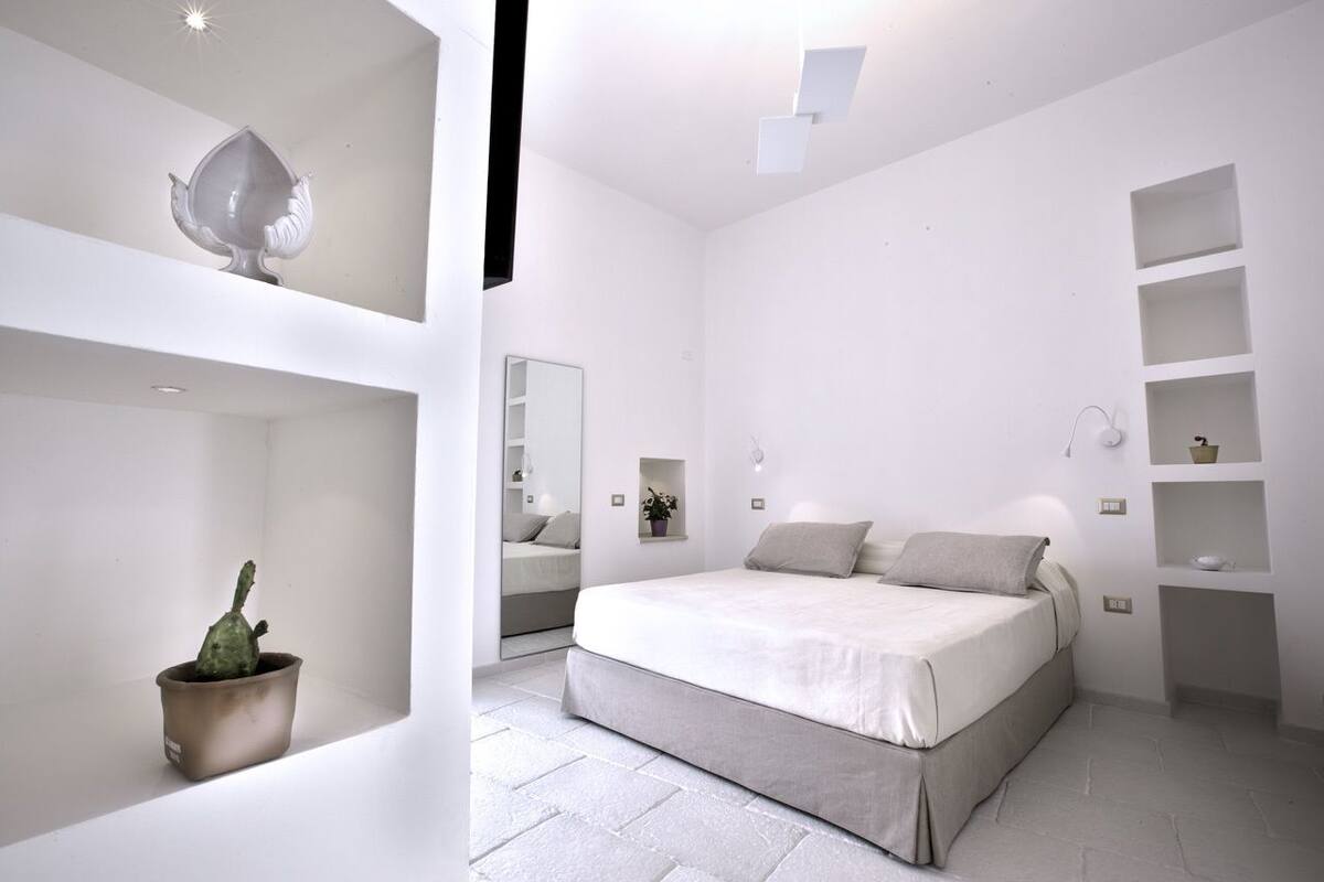 Une chambre à coucher au style minimaliste, avec un lit, des étagères et une plante en pot.