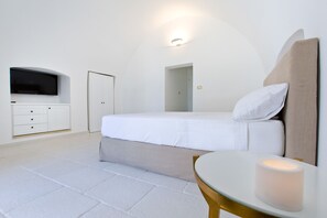 Une chambre à coucher moderne avec un lit, une télévision, une table de chevet avec une bougie et une porte.
