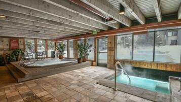 A spa area with a hot tub, a small pool, and a seating area with potted plants.