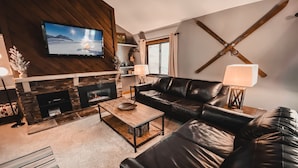 A modern living room with a fireplace, leather sofa, and a television mounted on the wall. - Flying Dutchman 1174 (Keystone)