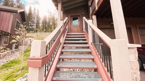 A wooden staircase leading to a door with a window, surrounded by a stone wall and a railing. - Alders 854 Independence Rd (Keystone)