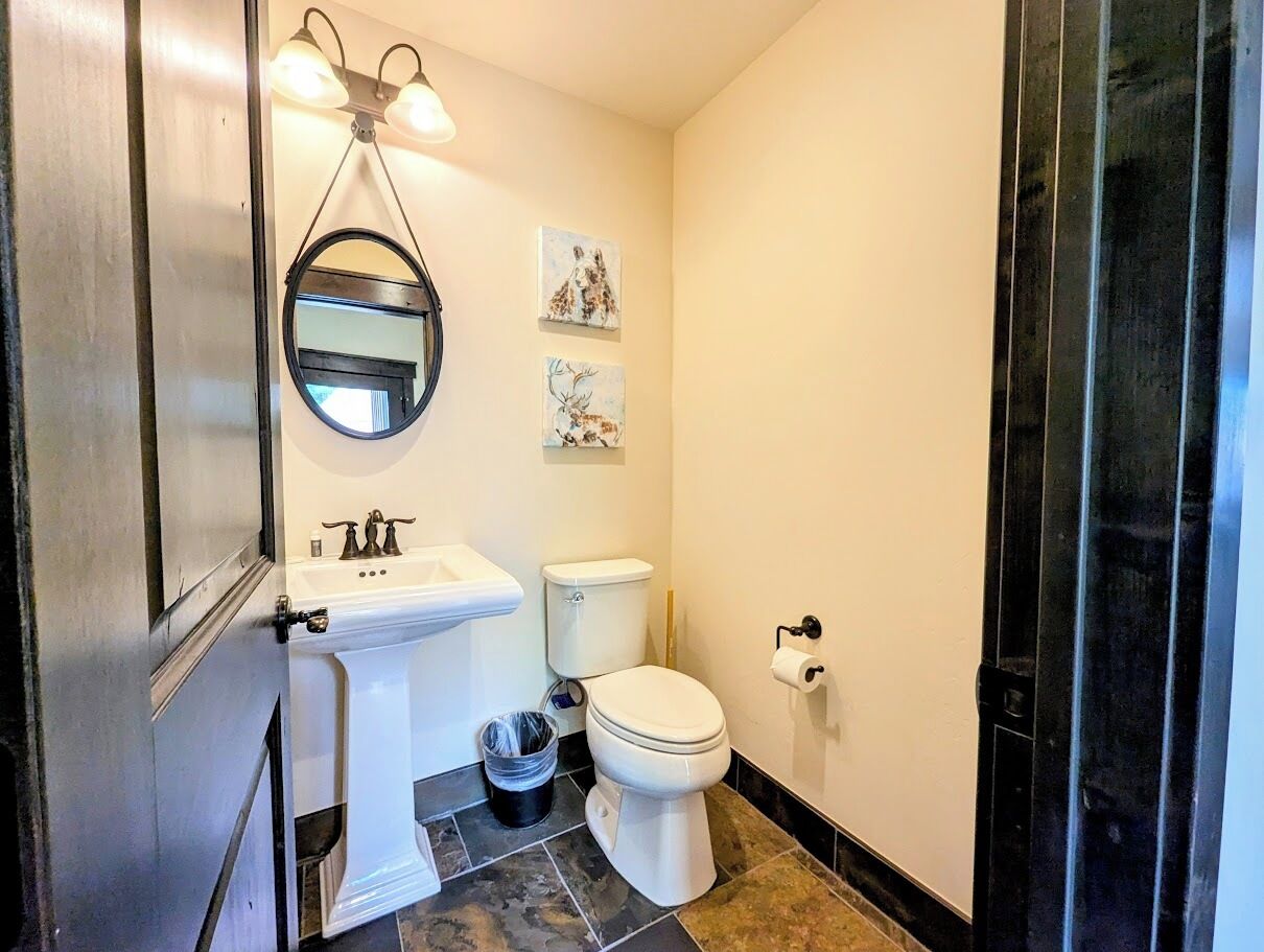A bathroom with a white sink, toilet, and a mirror. There are two wall-mounted lights above the mirror.