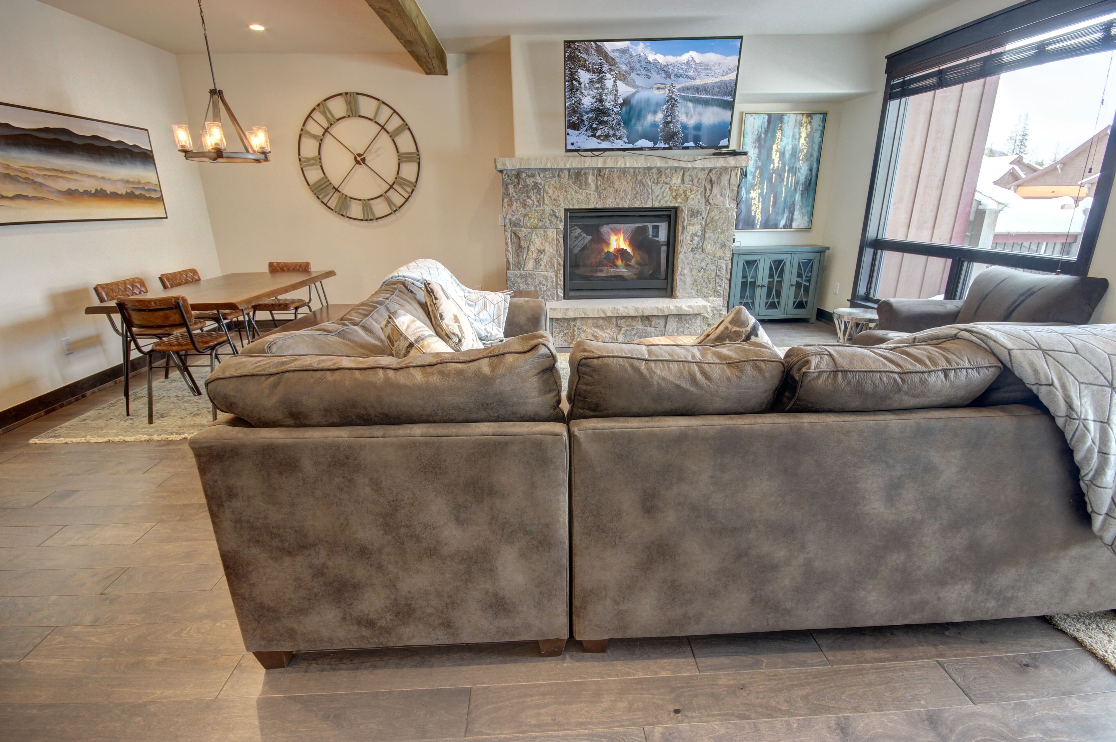 A living room with a fireplace, a dining area, and a large window.