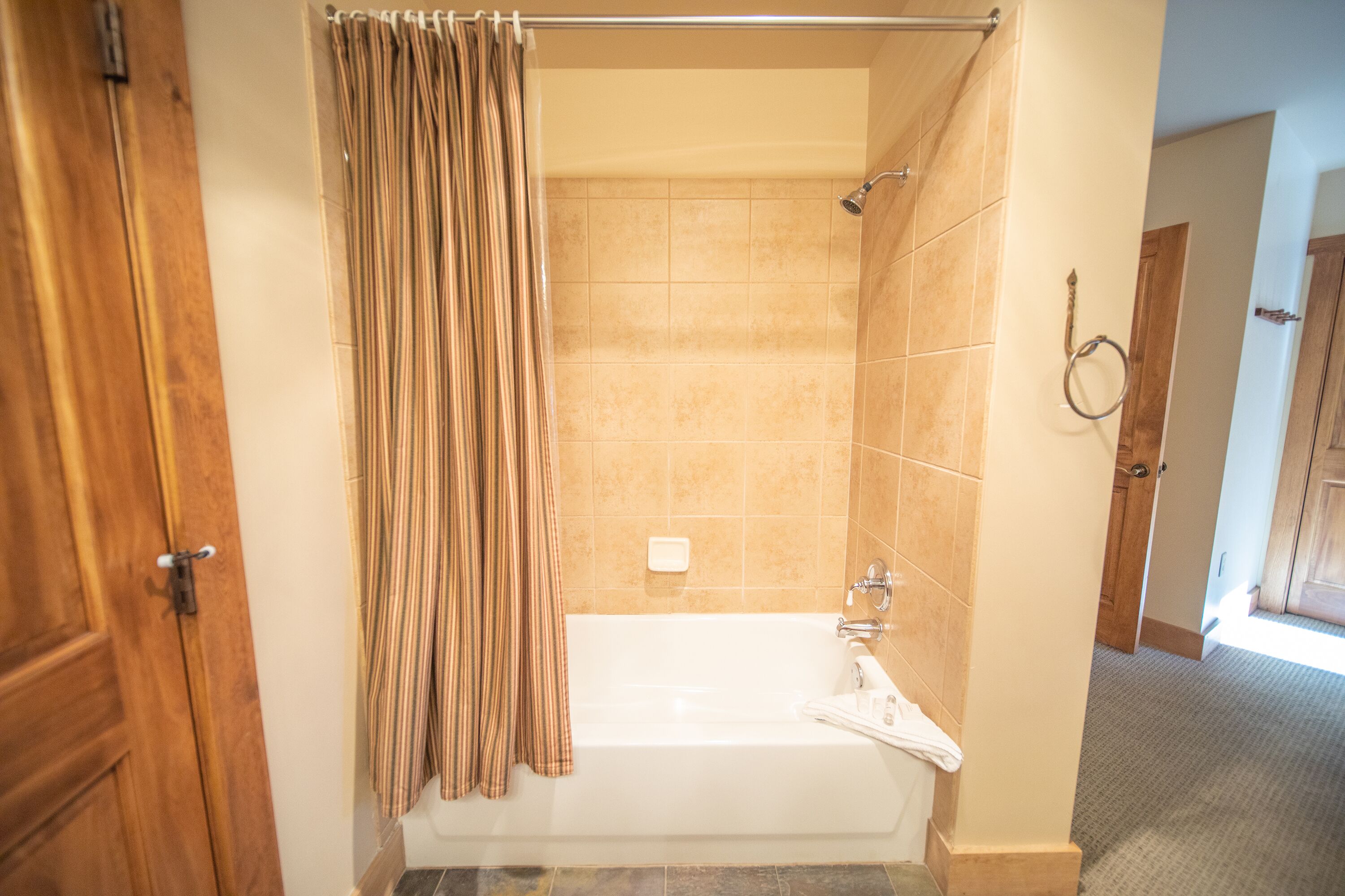 A bathroom with a bathtub, shower, and a wooden door.