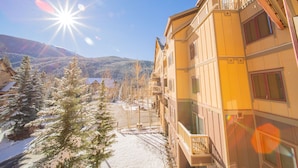 A multi-story building with balconies, a snow-covered ground, and a mountainous backdrop. - Red Hawk Lodge 2264 (Keystone)