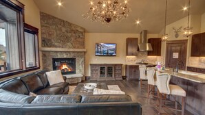 A modern living room with a fireplace, leather sofa, and a stone accent wall. - River Run Townhomes 96 (Keystone)