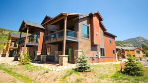 A modern multi-story building with balconies, stone pillars, and a mountainous backdrop. - River Run Townhomes 96 (Keystone)