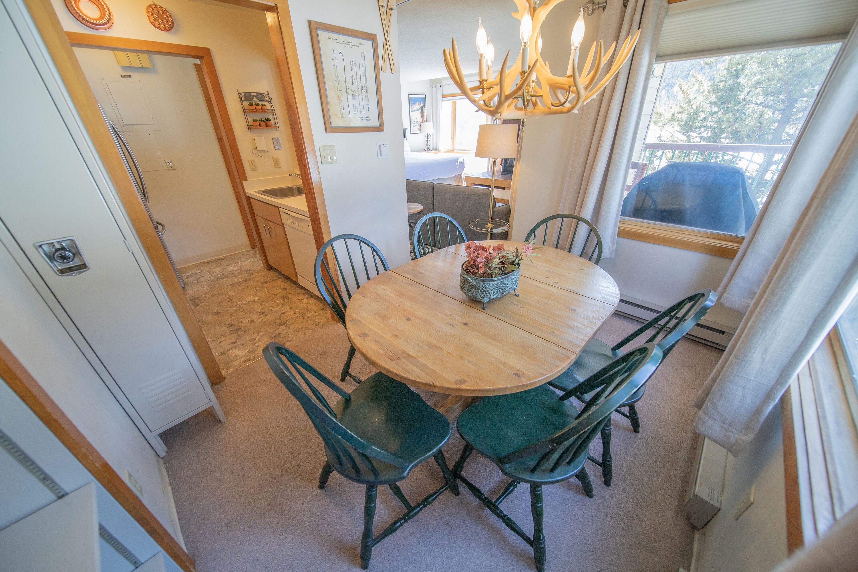 A dining area with a round wooden table, green chairs, and a chandelier.