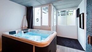A modern room with a glass-enclosed hot tub, a door leading to a balcony, and a brick wall. - Le Comptoir industriel (Lille)