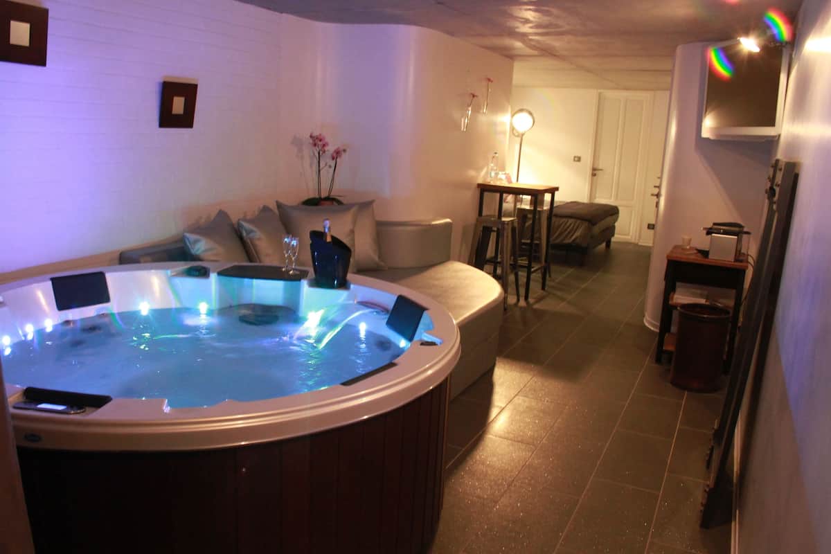 A hot tub in a room with a sofa, a small table, and a lamp.