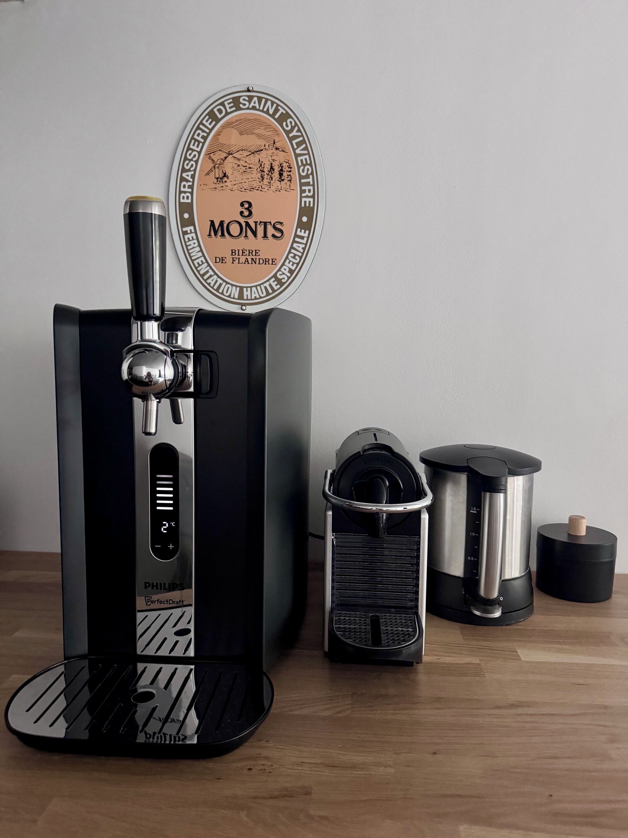 Une machine à café dotée d’un écran numérique, une cafetière et une presse à café, le tout posé sur une surface en bois.