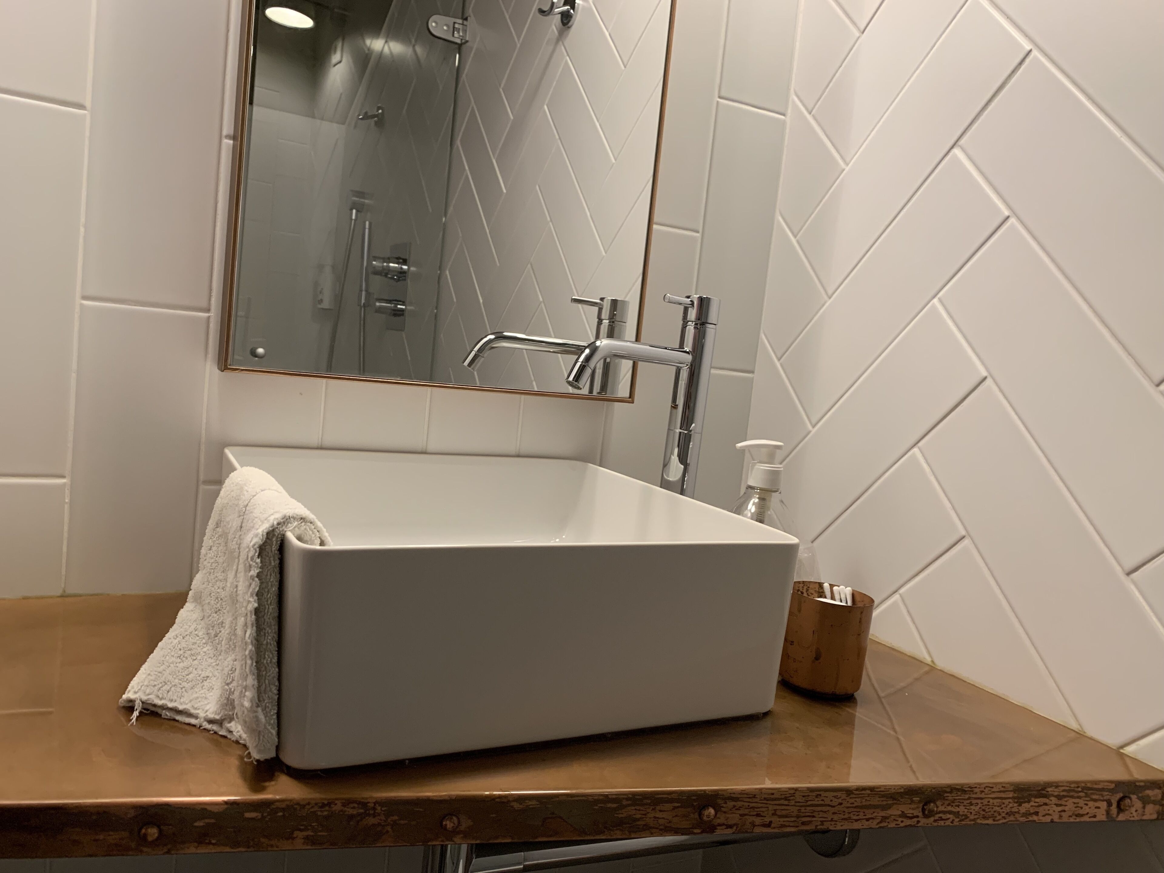 Un bagno con un lavabo rettangolare, uno specchio e una doccia.