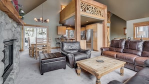 A spacious living area with a fireplace, leather sofas, a dining table, and a kitchen in the background. - Cabin in the Pines 4 (Keystone)