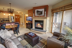 A living room with a fireplace, a dining area, and a kitchen. - Silver Mill 8164 (Keystone)
