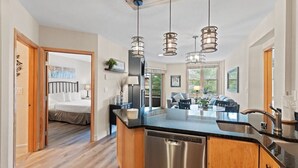 A modern kitchen with a central island, stainless steel appliances, and pendant lighting. - Silver Mill 8164 (Keystone)