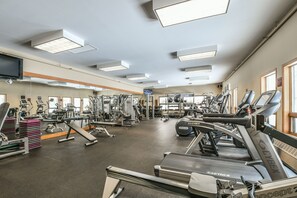 Un gimnasio con cintas de correr, máquinas de pesas y un espejo grande.