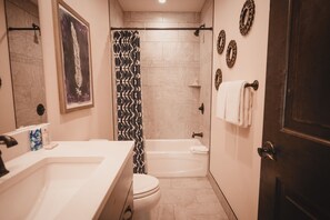 Ein Badezimmer mit Badewanne, Toilette und Waschbecken. An den Wänden befinden sich dekorative Teller und ein Duschvorhang.