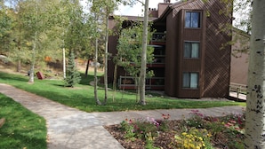 A modern building with a flat roof, large windows, and a well-maintained garden with various plants and flowers.