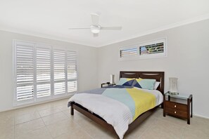 A bedroom with a bed, a nightstand, a ceiling fan, and a window with blinds. - Dolphins 2, 7 Commodore Crescent, (Port Macquarie)