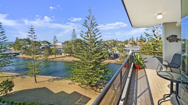 A balcony with a view of a lake, surrounded by trees and buildings. - Sundial 503, 8-10 Hollingworth Street, (Port Macquarie)