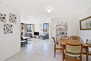 A spacious living area with a dining table, two sofas, a TV, and a bookshelf. - Sundial 503, 8-10 Hollingworth Street, (Port Macquarie)