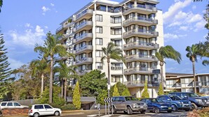 A multi-story residential building with balconies, parked cars, and surrounding palm trees. - Sundial 503, 8-10 Hollingworth Street, (Port Macquarie)