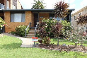 A two-story house with a brick facade, a front porch, and a staircase leading to the entrance. - Breakaway, 11 Scott Street, (Crescent Head)