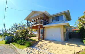 A two-story house with a balcony, a garage, and a well-maintained garden. - Beach Club 2, 5 Gowing Street, (Crescent Head)