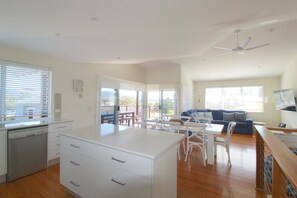 A spacious living area with a kitchen, dining table, and a large sofa. - Beach Club 2, 5 Gowing Street, (Crescent Head)