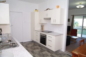 A compact kitchen with white cabinetry, a built-in oven, and a countertop with a sink. - Fleur Cottage, 7 Willow Street, (Crescent Head)