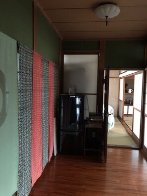 A hallway with patterned curtains, a ceiling fan, and a wooden floor. - Seikaso (Kunisaki)