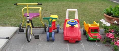 Un espacio de juegos infantiles con un triciclo, un coche de juguete y un tractor de juguete.