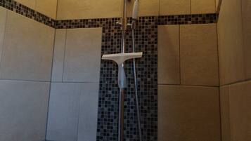Een douche met een handdouche, een wandmengkraan en een bedieningshendel.