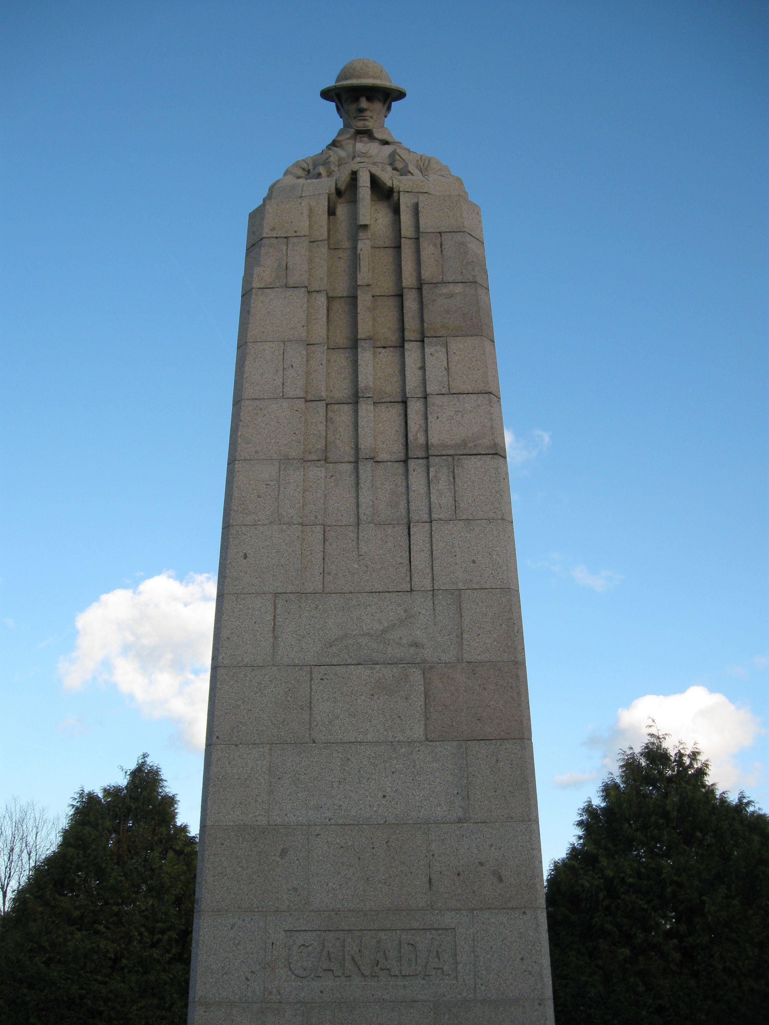A tall stone monument with a figure wearing a hat at the top, and the word "CANADA" carved at the base.