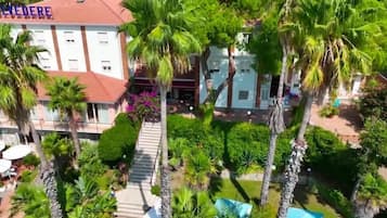 Un hotel con tetto rosso, circondato da palme e un giardino curato.