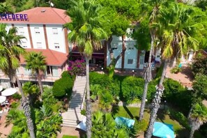 Ein Hotel mit rotem Dach, umgeben von Palmen und einem gepflegten Garten.