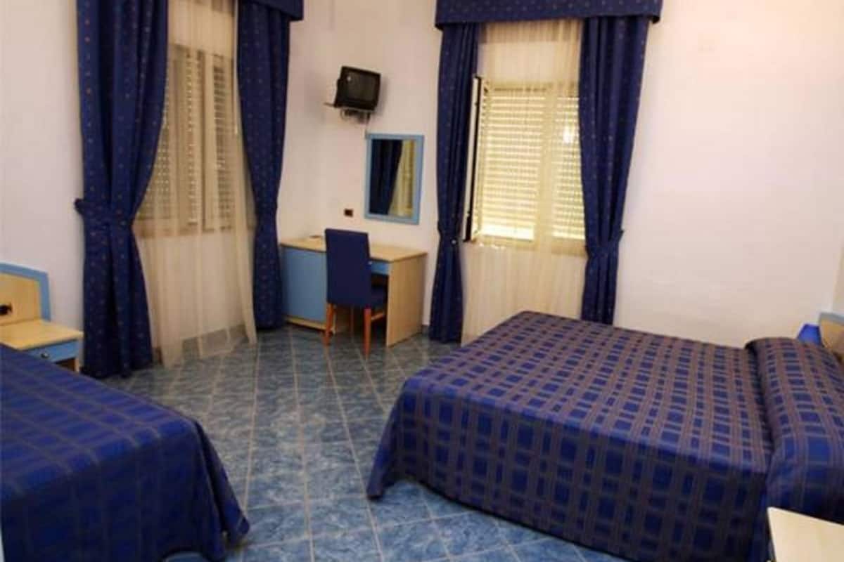 Une chambre d’hôtel avec deux lits, un bureau, une chaise et un téléviseur.