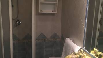 Un bagno con doccia vetrata, lavabo con specchio e portasciugamani.
