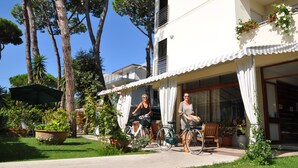 Un edificio a due piani con un balcone, piante in vaso e biciclette.