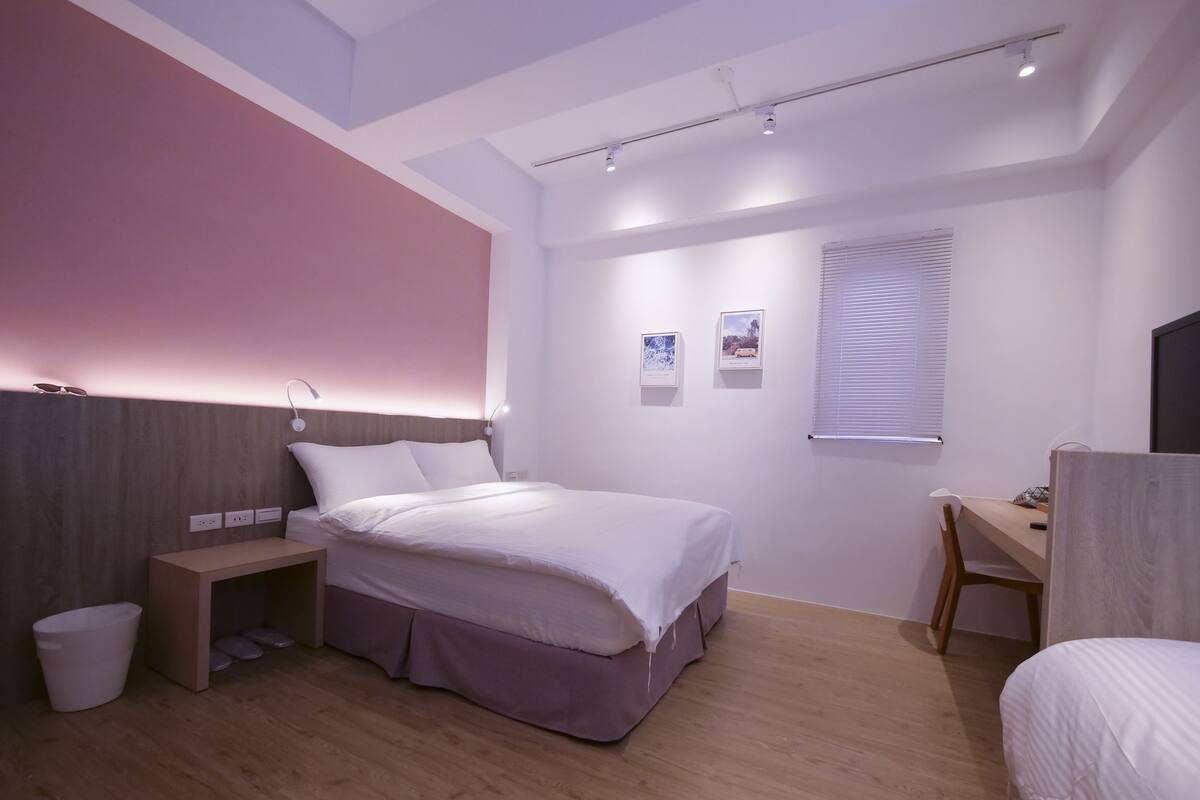 A modern bedroom with a bed, bedside table, and a desk.