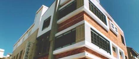 A modern multi-story building with a brick facade and large windows.