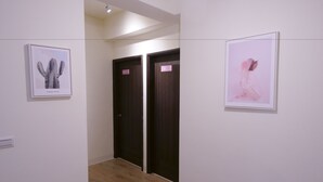 Un pasillo con dos puertas, cada una con una placa de identificación, y dos cuadros enmarcados en las paredes.