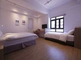 A modern bedroom with two beds, a desk, and a TV.