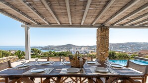 A table set for dining with a view of the sea and a pool. - DreamLike Villas Mykonos (Mykonos)