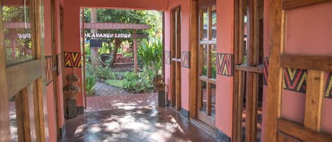 Un pasillo con recepción, puertas de madera y un cartel para Okavango Lodge.