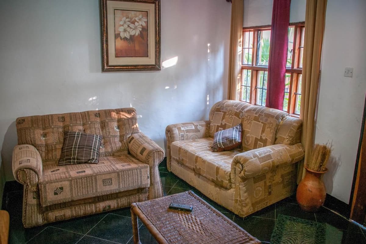 A living room with two patterned sofas, a small table, and a window with curtains.
