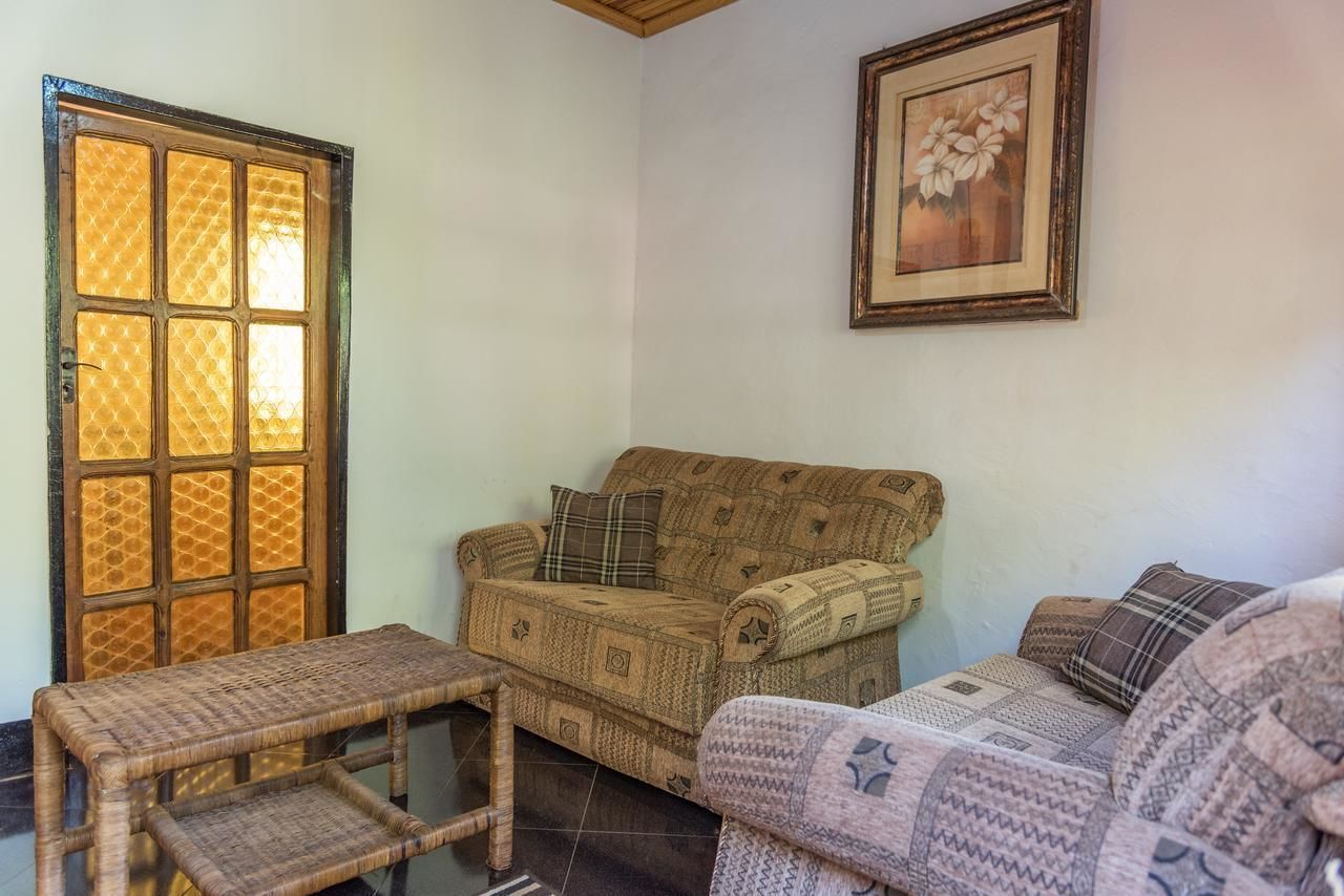 Ein Wohnzimmer mit einem gemusterten Sofa, einer kleinen Holzbank und einem floralen Bild in einem Rahmen an der Wand.