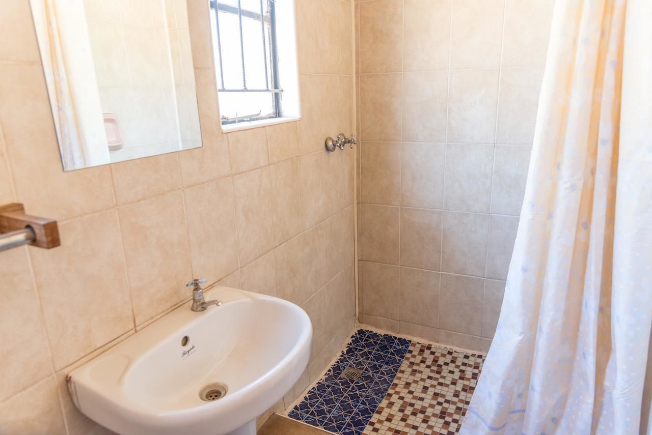 Un bagno con lavandino, finestra e zona doccia.