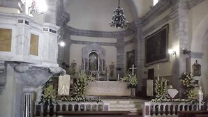 Ein Kircheninneres mit Kirchenbänken, Altar und einer Chandelüster.